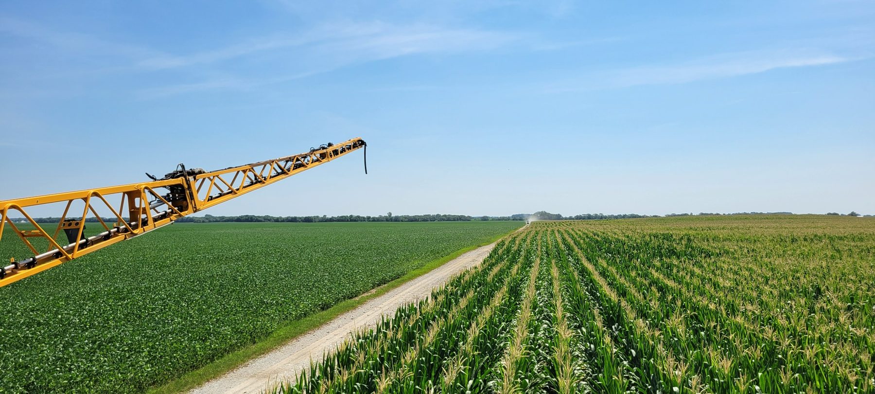 Sprayer boom applying crop protection products across corn and soybean fields in Ohio
