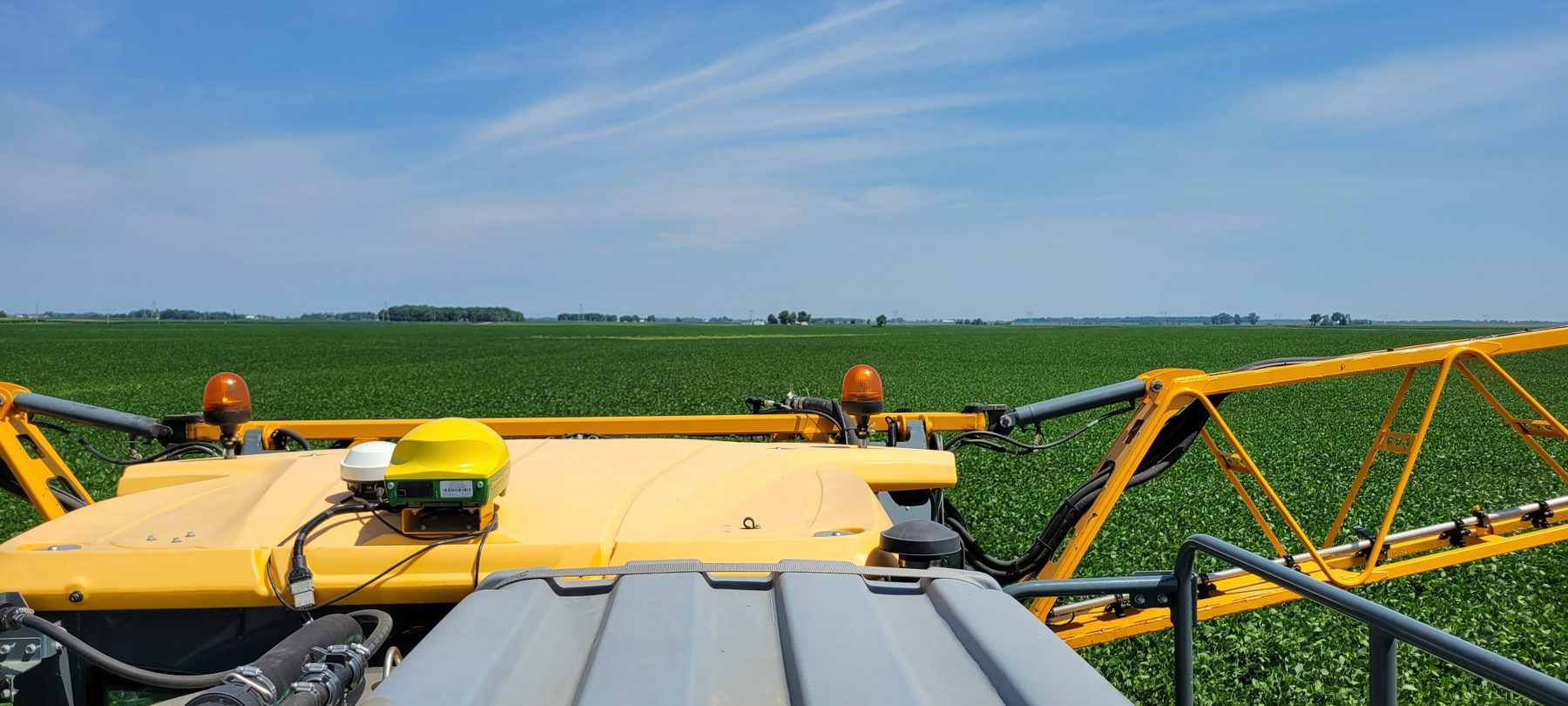 Sprayer tank and boom setup over a soybean field