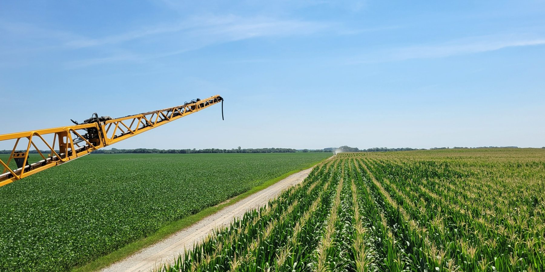 High-clearance sprayer making an in-season pass across corn and soybeans